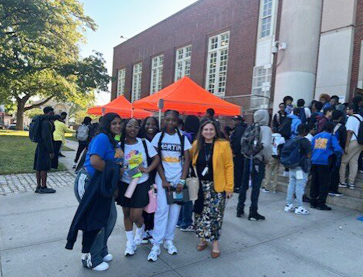 Group of girls with principal outside front of school building