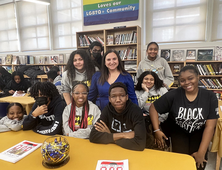 Principal with a group of happy students posing for a picture in the library